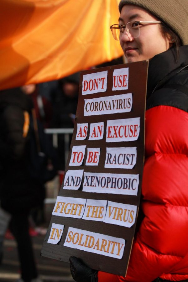 A woman carries a sign during the 2020 Lunar New Year Parade in an effort to bring awareness to the xenophobia in the United States. 
