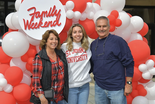A family poses in front of Family Weekend decor.
